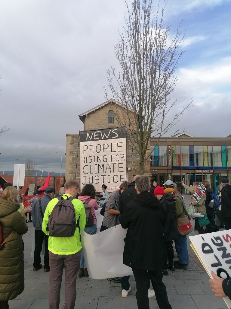 News - people rising for climate justice banner in front of waterside train station
